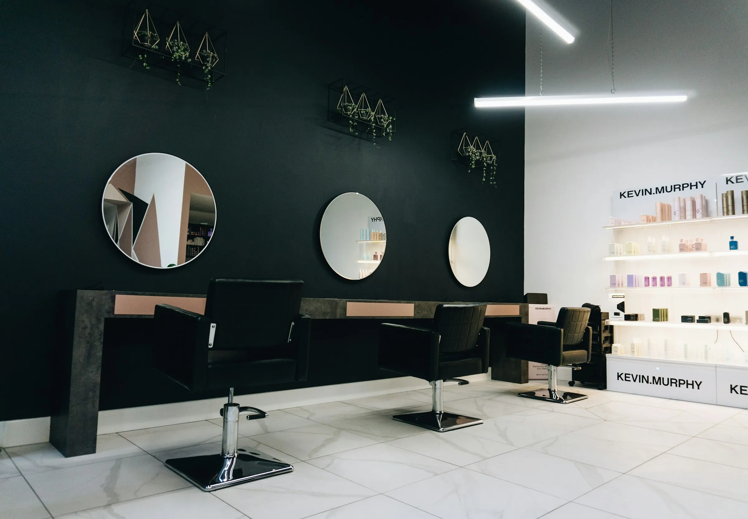 Salon fryzjerski: trzy fotele przed okrągłymi lustrami